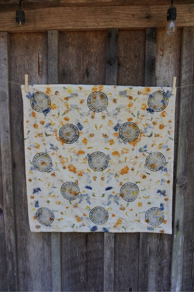 Decorative tea towel with circular patterns hanging on a wooden wall